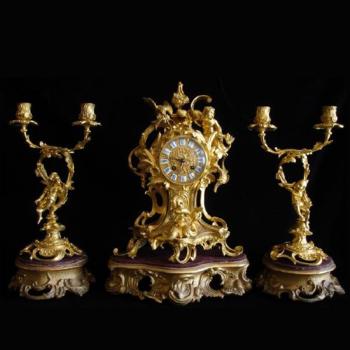 Bronze clock with candlesticks on wooden pedestals Bronze clock with candlesticks on wooden pedestals