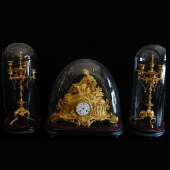 The bronze clock with candlesticks under glass bel The bronze clock with candlesticks under glass bel