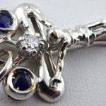 White gold cross with diamond and paired blue sapp White gold cross with diamond and paired blue sapp