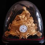 The bronze clock with candlesticks under glass bel The bronze clock with candlesticks under glass bel