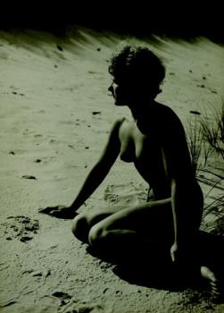 A young female kneeling on a beach